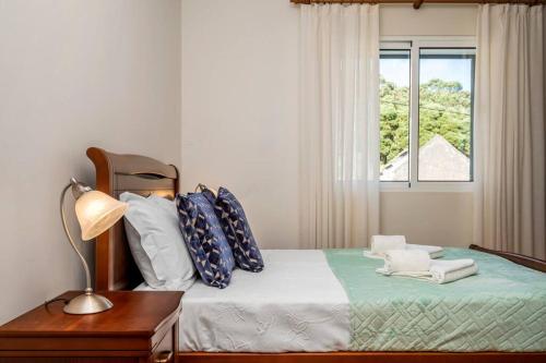 Un dormitorio con una cama con una lámpara y una ventana. en Casa do Palheiro Ribeirinho, en Porto Moniz