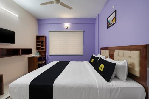 1 dormitorio con 1 cama grande y paredes moradas en Super Collection O Veritas Grand, en Bangalore