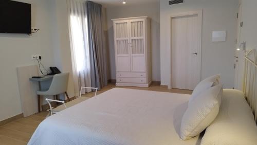 1 dormitorio con 1 cama blanca grande y escritorio en Hotel Vinoteca Alquezar - Adults Only - en Alquézar