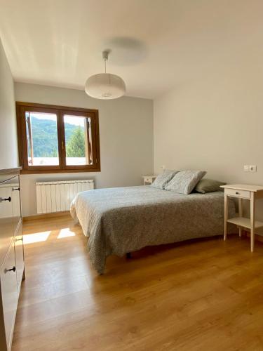 a white bedroom with a bed and a table at Apartamento Balcón del Ésera in Villanova