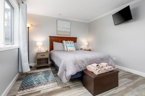 a white bedroom with a bed and a tv at Modern Golfview Condo near the Grand Traverse Bay in Williamsburg