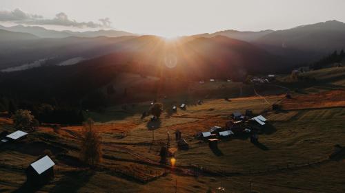 a group of people standing in a field with the sun setting at Pleta View in Vatra Dornei