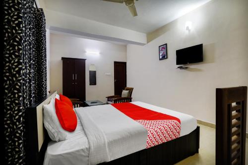 a bedroom with a bed with red pillows and a tv at OYO Flagship Arrows Tourist Home in Cochin