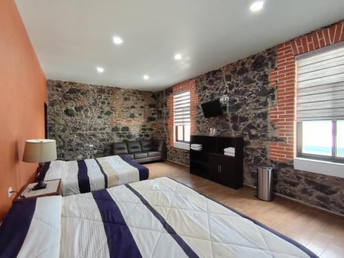 a bedroom with brick walls and a bed and a television at Hotel Xochicaltzin in Atlixco