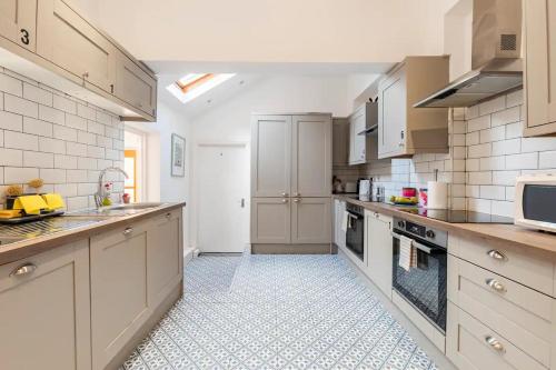 a large kitchen with white cabinets and a tile floor at Northumberland Boutique Guest House #2 in Coventry