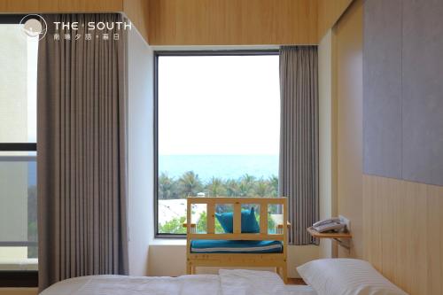 a bedroom with a bed and a window with a chair at The South-Sunset in Hengchun South Gate