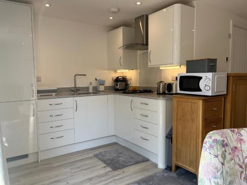 a kitchen with white cabinets and a microwave at Self contained annex with full kitchen in Witney
