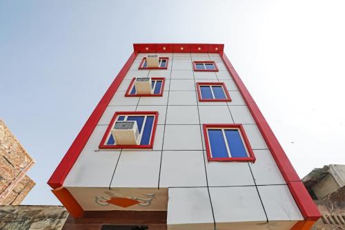 a tall white building with red and white windows at OYO Hotel Sk Inn in Ghaziabad