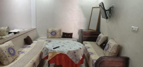 a room with two beds and a table in it at Dar fatima in Temara