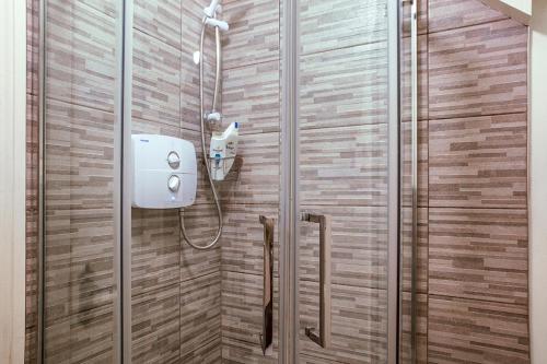 a shower in a bathroom with a wooden wall at The Ridgewood Lodge in Newbridge