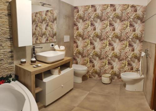 a bathroom with a sink and a toilet and a wallpaper at Donna Rosa in Pagani