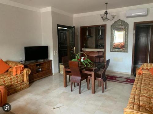 a living room with a table and chairs and a television at Super maisons a 2 pas d'agadir in Ait Melloul