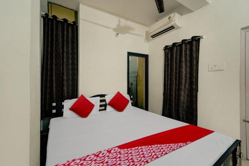a bedroom with a white bed with red pillows at OYO Flagship Residence Inn Guest House in Patna
