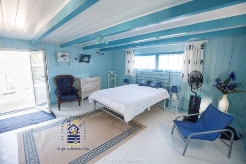 - une chambre avec des murs bleus, un lit et une chaise dans l'établissement Ma cabane au bord de l'eau, à La Tremblade