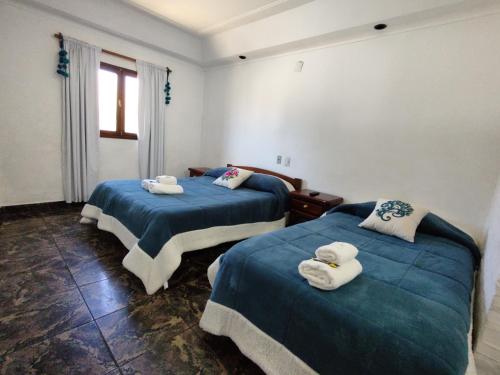 2 camas en una habitación con sábanas azules y toallas en Hotel Los Cuartos en Tafí del Valle