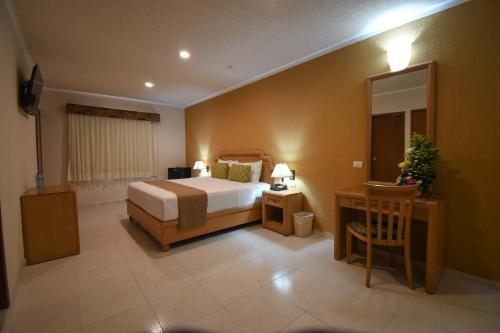 a bedroom with a bed and a table and a mirror at Tecnohotel Itzáes in Mérida
