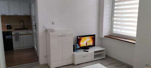 a white living room with a television on a white cabinet at Kawalerka blisko GÓR in Głuchołazy