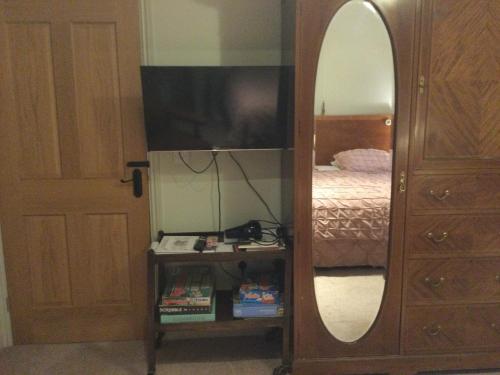 ein Schlafzimmer mit einem Spiegel, einem Bett und einer Kommode in der Unterkunft STACK YARD COTTAGE. in Cambridge