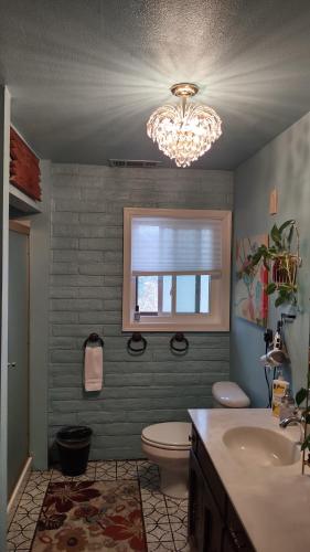 a bathroom with a sink and a toilet and a chandelier at Rustic Rooms by Kings Canyon & Sequoia National Parks in Squaw Valley