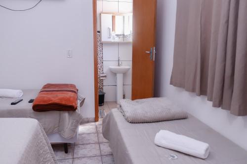 a small room with two beds and a sink at Pousada Bela Vista in Inconfidentes