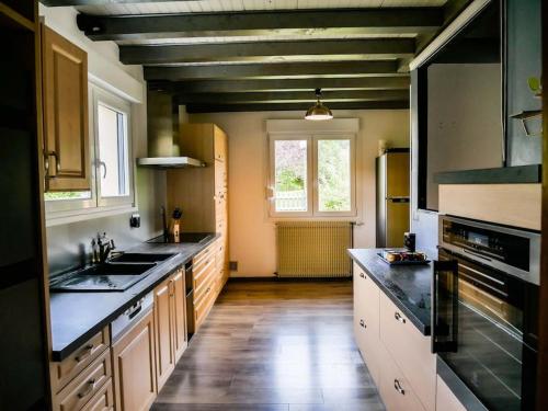 Il comprend une grande cuisine avec du parquet et des comptoirs noirs. dans l'établissement Chalet Marie-Louise - Gérardmer, à Gérardmer