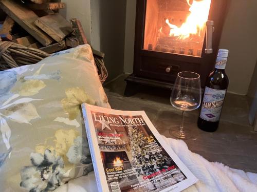 a magazine and a bottle of wine and a glass at Tranquil Appleby Retreat for 6 Guests with Hot Tub in Appleby