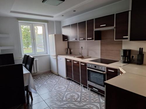 a kitchen with brown cabinets and a table and a window at Apartament Maria 