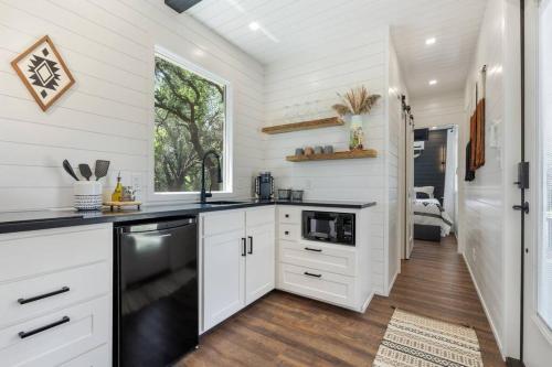a kitchen with white cabinets and a black dishwasher at The Lonely Bull Luxury Container Home on 5 Acres in Weatherford