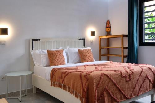 sypialnia z łóżkiem z pomarańczowym kocem w obiekcie Villa Umy w mieście Ngaparou