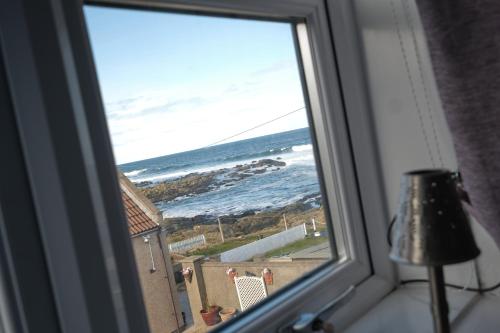 a window with a view of the ocean at Craigmile Cottage in Fraserburgh