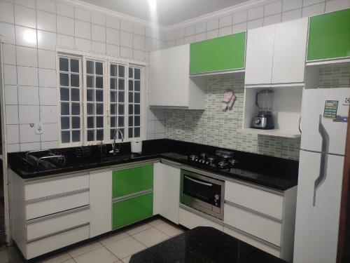 a kitchen with green and white cabinets and a refrigerator at Casa ampla e linda com área de lazer in Uberlândia