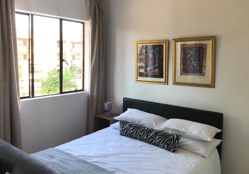 a bedroom with a bed with two pillows and a window at Studio Eazi in Midrand