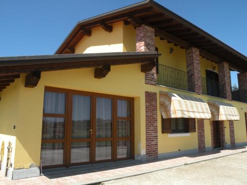 a yellow house with glass doors and a balcony at B&B Da Levi Piana Del Sole in Rivalta Bormida