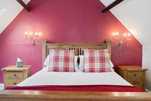a bedroom with a bed with a red wall at Beautiful Secluded 2 Bedroom Coach House in Nottingham