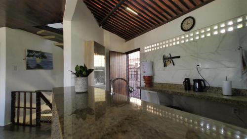 uma cozinha com um balcão e um relógio na parede em Casa inteira, sauna, piscina ozonizada, praia Enseada dos Corais, Cabo de Santo Agostinho, Pernambuco, Nordeste, Brasil em Cabo de Santo Agostinho