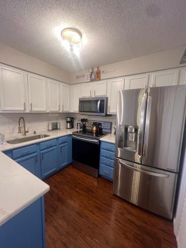 a kitchen with blue cabinets and a stainless steel refrigerator at Spacious Corporate Condo - 2bd/2ba in Madison