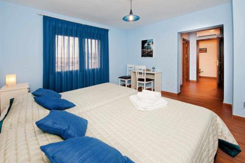 a bedroom with two large beds with blue pillows at Alojamientos Callejón del Pozo cerca Puy du Fou in Gálvez