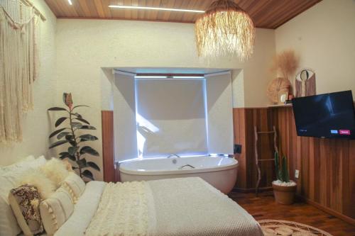ein Bad mit einer Badewanne und ein Fenster mit einer Badewanne in der Unterkunft Pousada Irreplaceable in Visconde De Maua