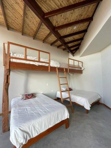 um quarto com 2 beliches e uma escada em Casa Natural em Los Órganos