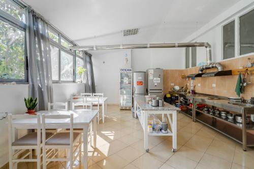 eine Küche mit weißen Tischen und Stühlen im Zimmer in der Unterkunft Hostel Hasta La Vista in Sarandë