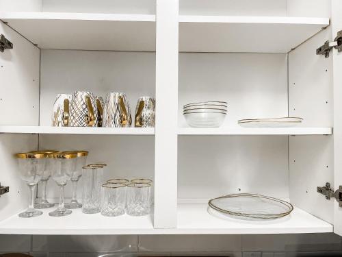 a white cabinet filled with glasses and plates at Dolly's Art Deco - Luxe Stay Near Broadway in Nashville