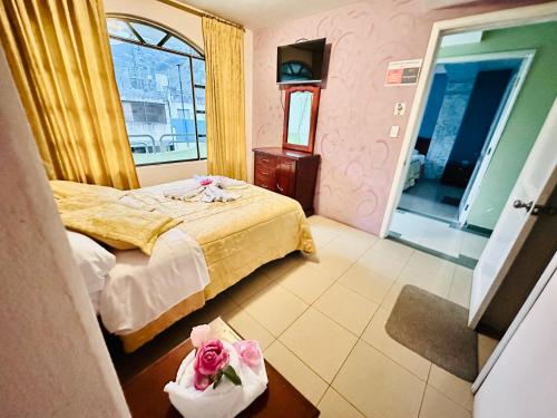 ein Schlafzimmer mit einem Bett und einem Tisch mit Blumen darauf in der Unterkunft Hostal Grand Rio in Baños