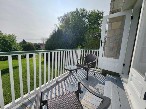a porch with two chairs and a table and a table at Auberge des Nuages in La Malbaie