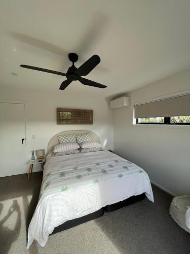 a bedroom with a bed with a ceiling fan at Private by the beach in Whitianga