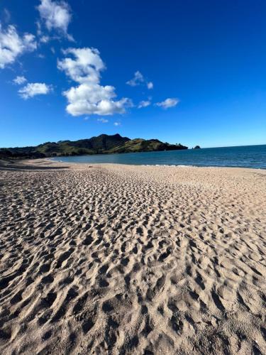 a sandy beach with a view of the ocean at Private by the beach in Whitianga