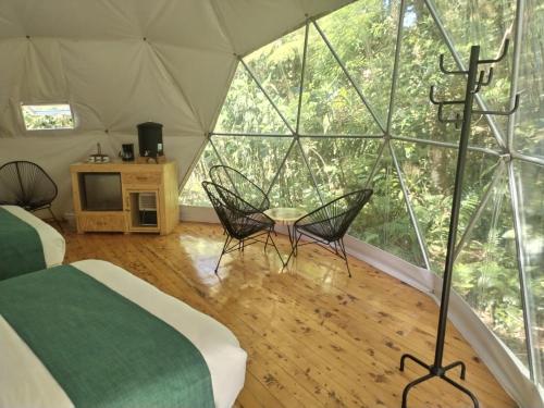 Una habitación con cama y sillas en una tienda de campaña en Refugio La Paz EcoGlamping, en San Ramón