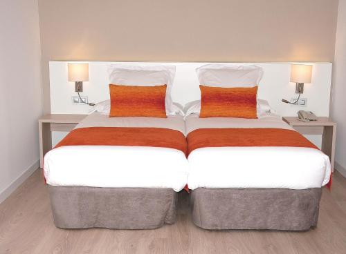 a bedroom with two beds with orange and white pillows at BQ Augusta Hotel in Palma de Mallorca