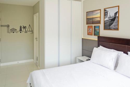 Schlafzimmer mit einem weißen Bett mit einem Kopfteil aus Holz in der Unterkunft Apartamento Aconchegante Beira-Mar Ondina in Salvador