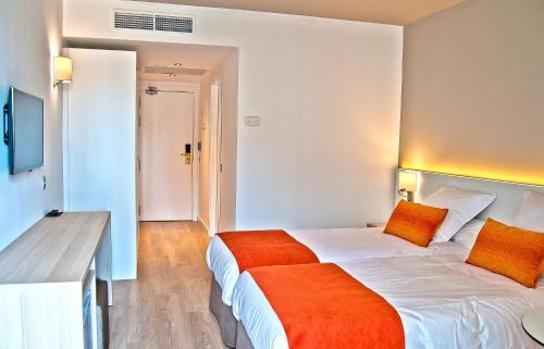 a hotel room with a large bed with an orange blanket at BQ Augusta Hotel in Palma de Mallorca