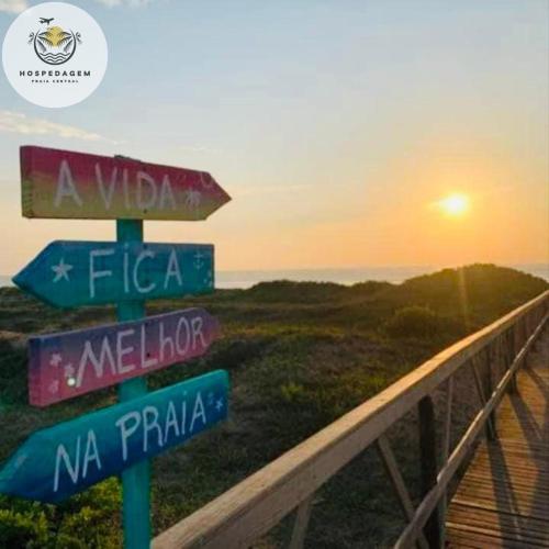 a pole with street signs in front of the ocean at Hospedagem Praia Central in Navegantes